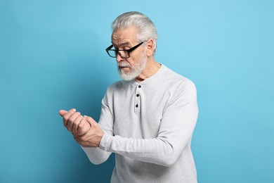 Photo of Arthritis symptoms. Man suffering from pain in wrist on light blue background