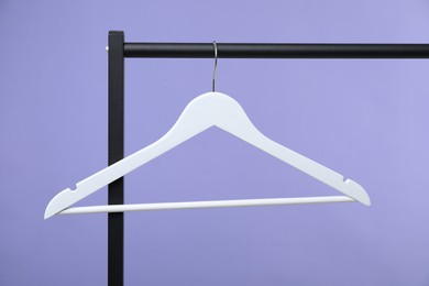 Photo of White clothes hanger on rack against purple background