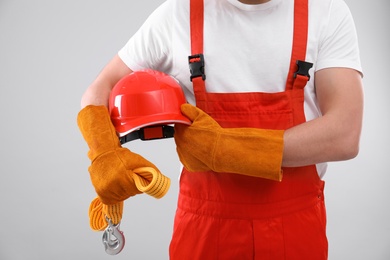 Male industrial worker in uniform on light background, closeup. Safety equipment