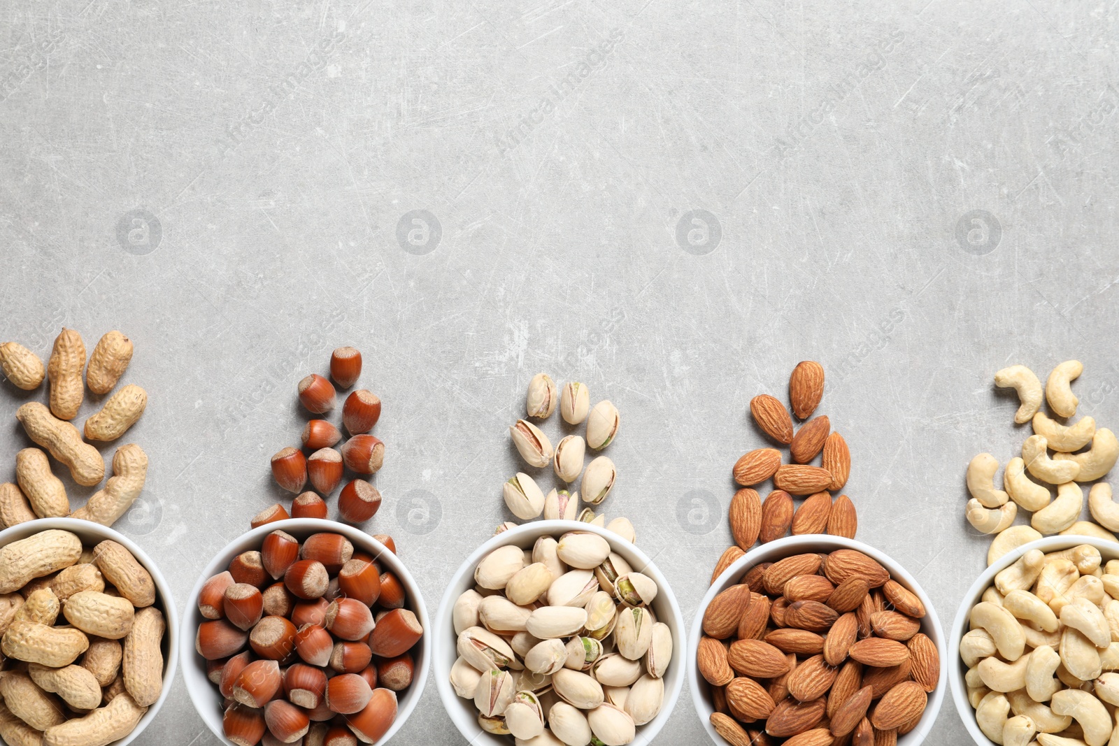 Photo of Flat lay composition with organic nuts and space for text on grey background, top view. Snack mix