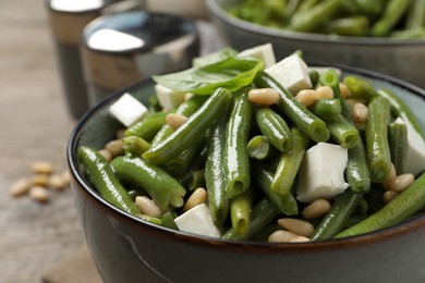 Photo of Delicious salad with green beans, pine nuts and cheese on table, closeup