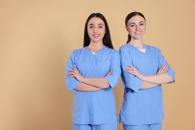 Nurses in medical uniforms on light brown background, space for text