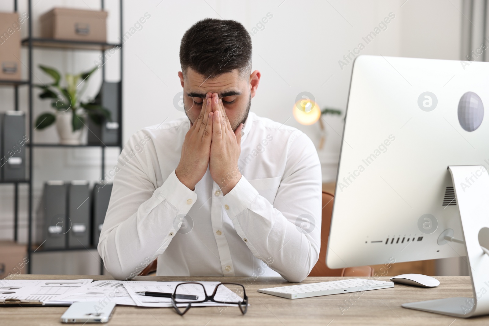Photo of Overwhelmed man sitting at table in office