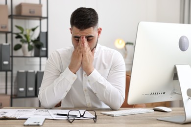 Overwhelmed man sitting at table in office