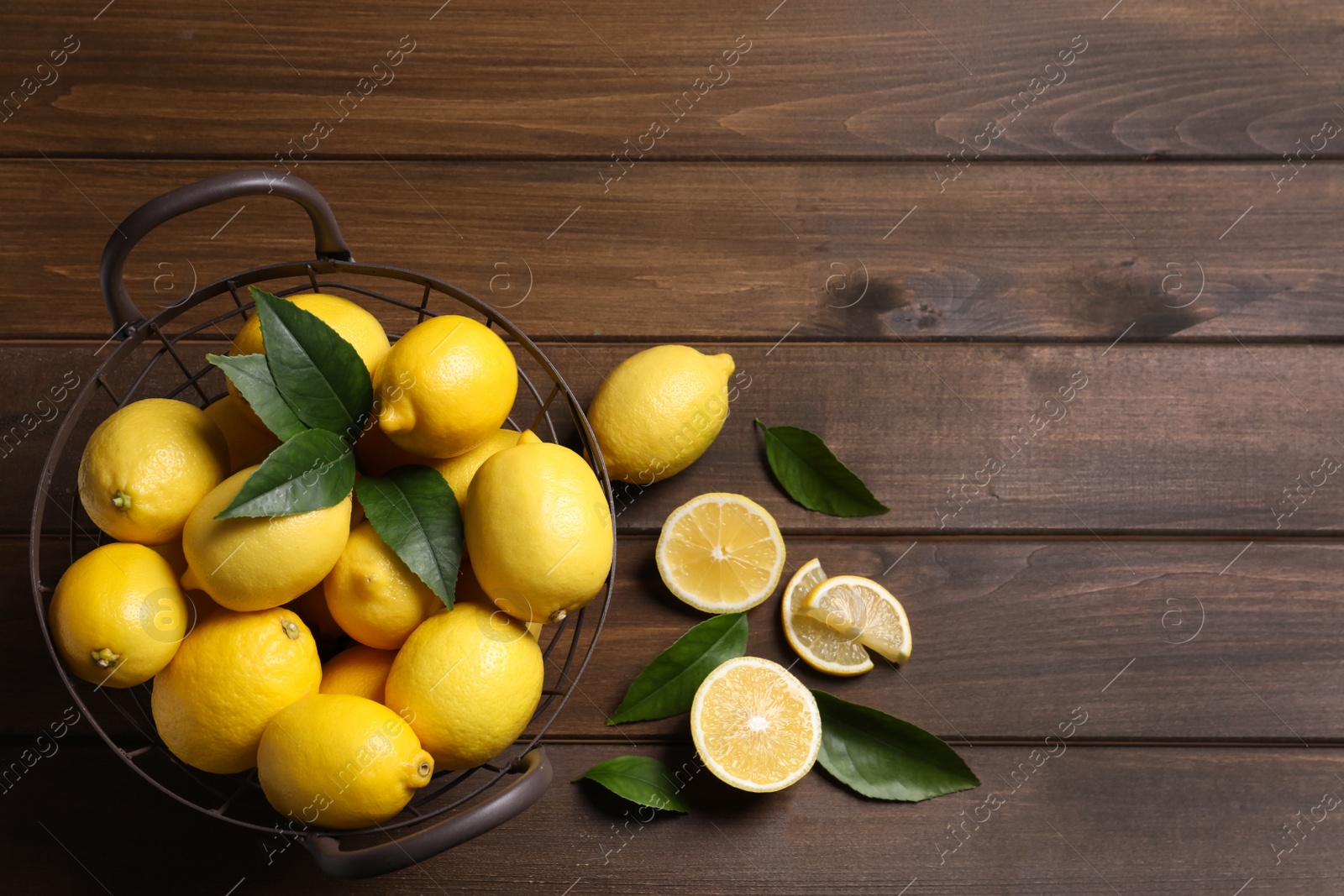 Photo of Many fresh ripe lemons with green leaves on wooden table, flat lay. Space for text
