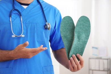 Photo of Male orthopedist showing insoles in clinic, closeup