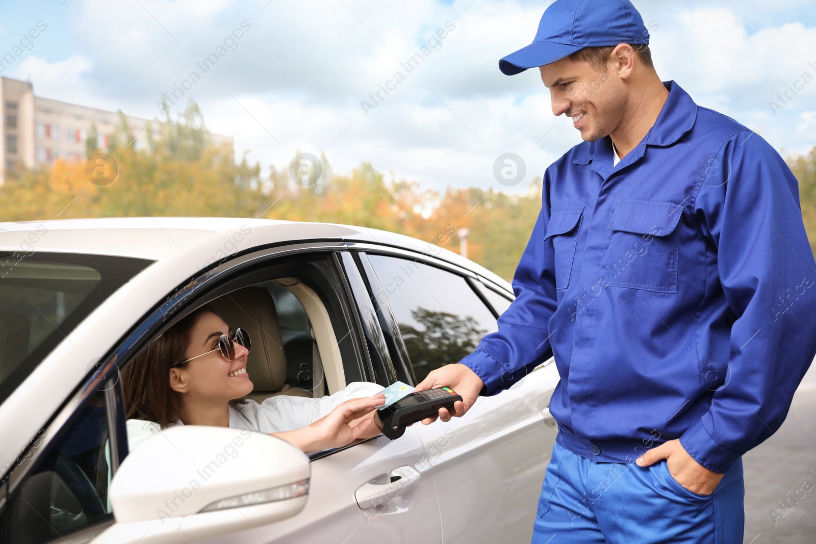 Photo of Woman sitting in car and paying with credit card at gas station