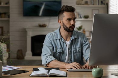 Man working with computer at table in home office, space for text