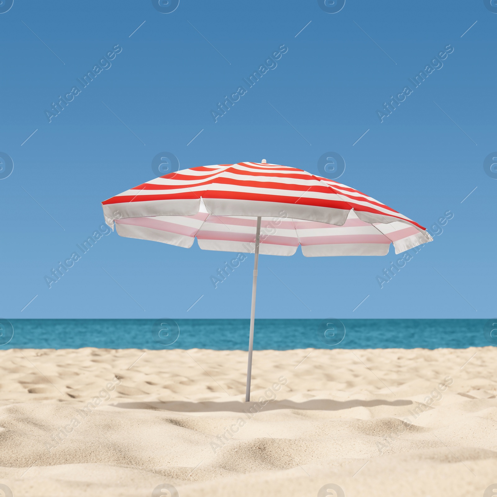 Image of Open big beach umbrella on sandy coast 