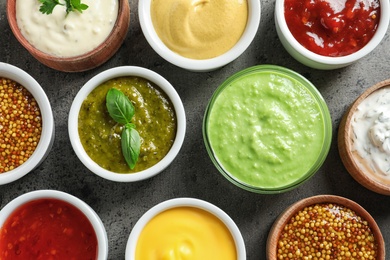 Set of different delicious sauces on grey table, top view