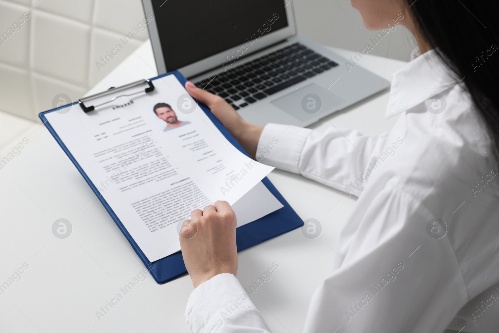 Photo of Human resources manager reading applicant's resume at white table, closeup