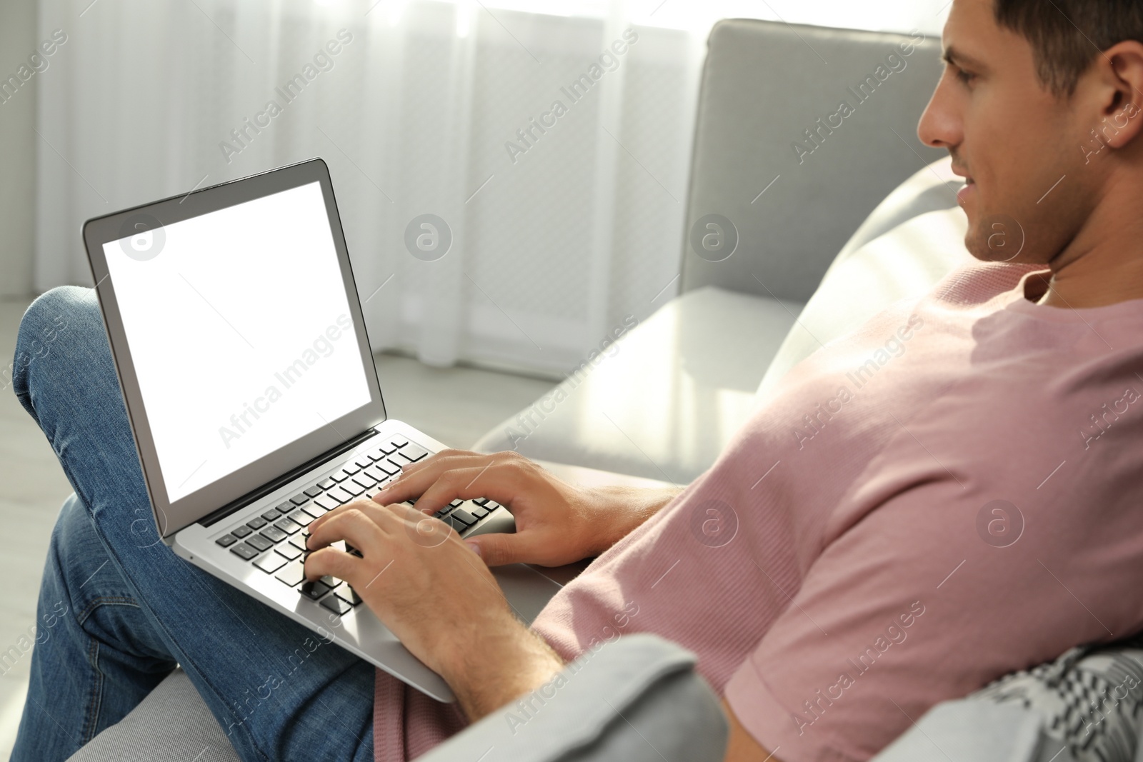 Photo of Man using laptop for search on sofa at home, closeup