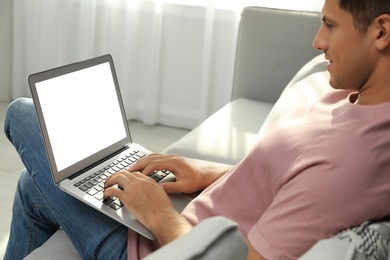 Photo of Man using laptop for search on sofa at home, closeup