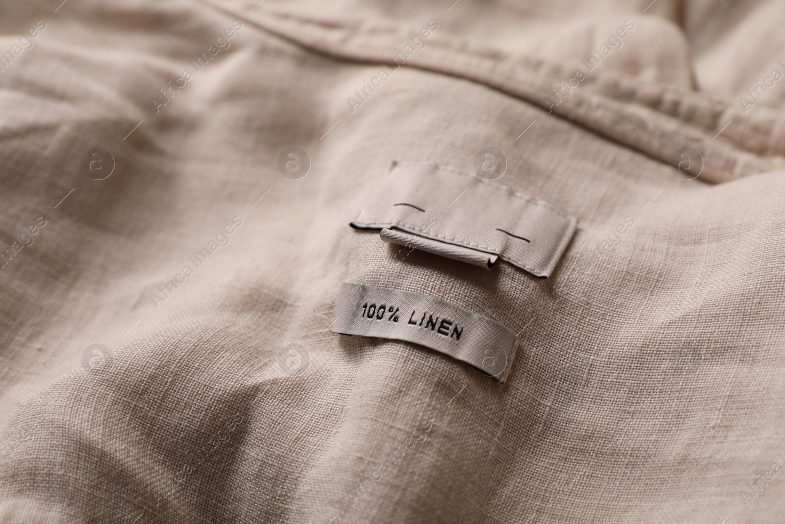 Photo of Clothing label on beautiful beige garment, closeup