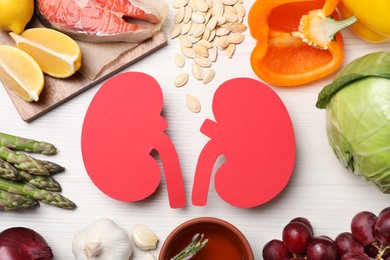 Photo of Flat lay composition with paper cutout of kidneys and different products on white wooden table