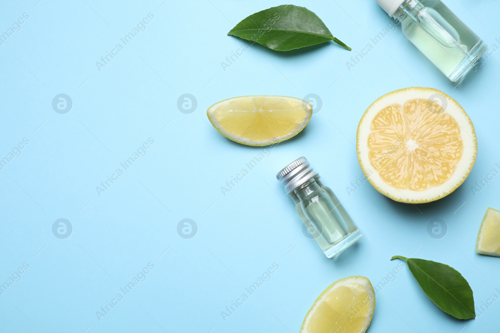 Photo of Flat lay composition with bottles of citrus essential oil on light blue background. Space for text