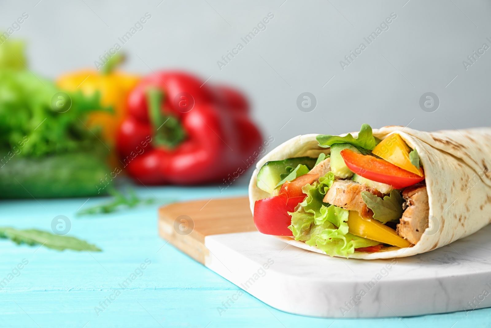 Photo of Delicious meat tortilla wrap on blue wooden table, space for text