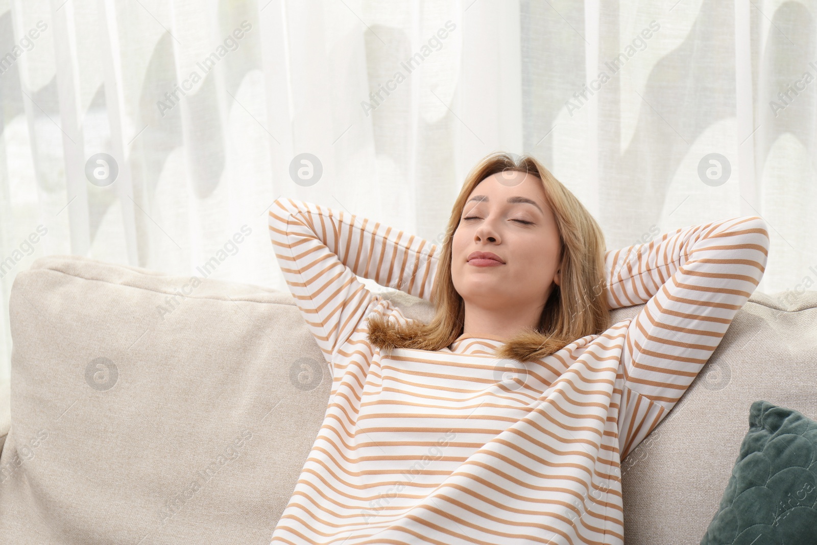 Photo of Beautiful young woman relaxing on sofa indoors