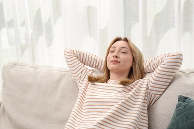 Beautiful young woman relaxing on sofa indoors