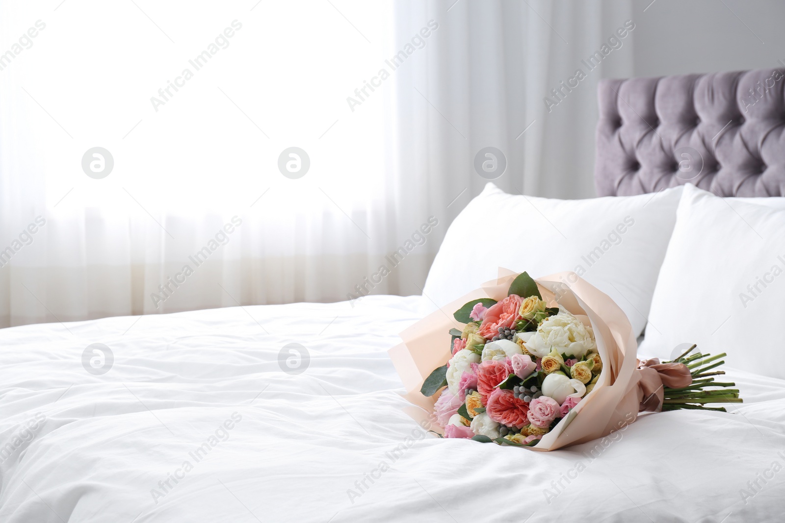 Photo of Beautiful flower bouquet on bed in light room. Space for text