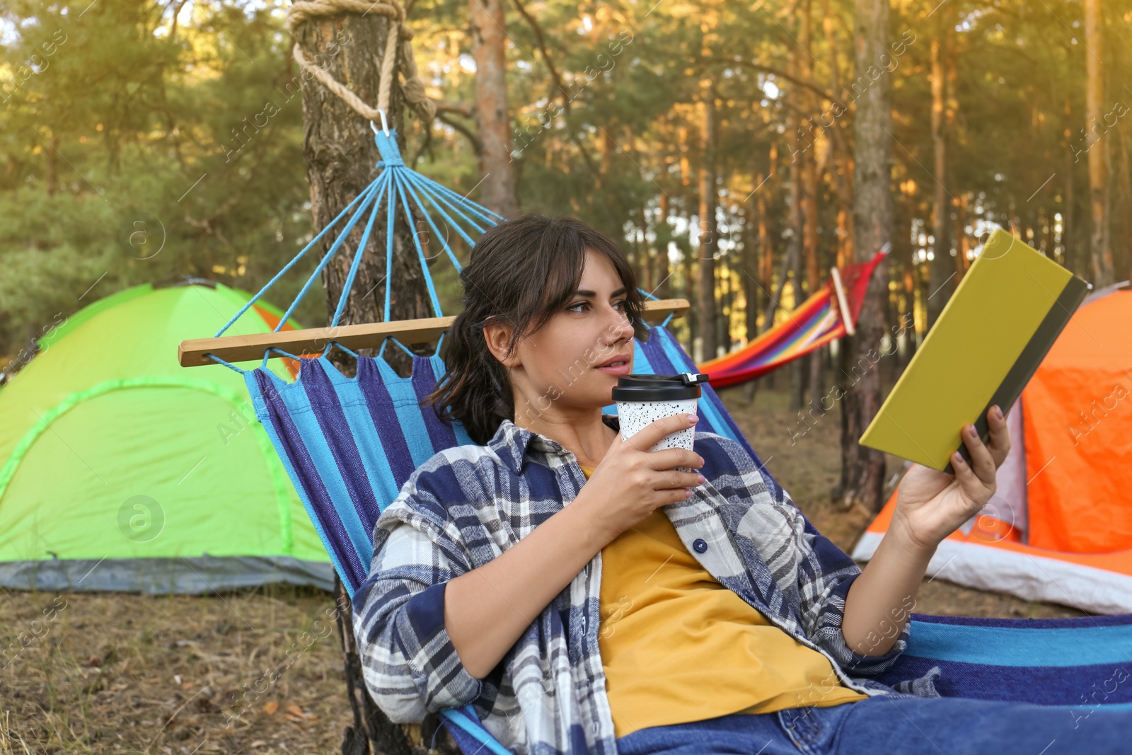 Photo of Woman with book resting in comfortable hammock outdoors