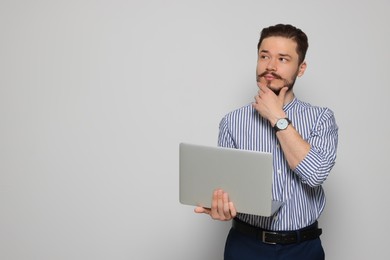 Photo of Pensive man using laptop on light grey background. Space for text