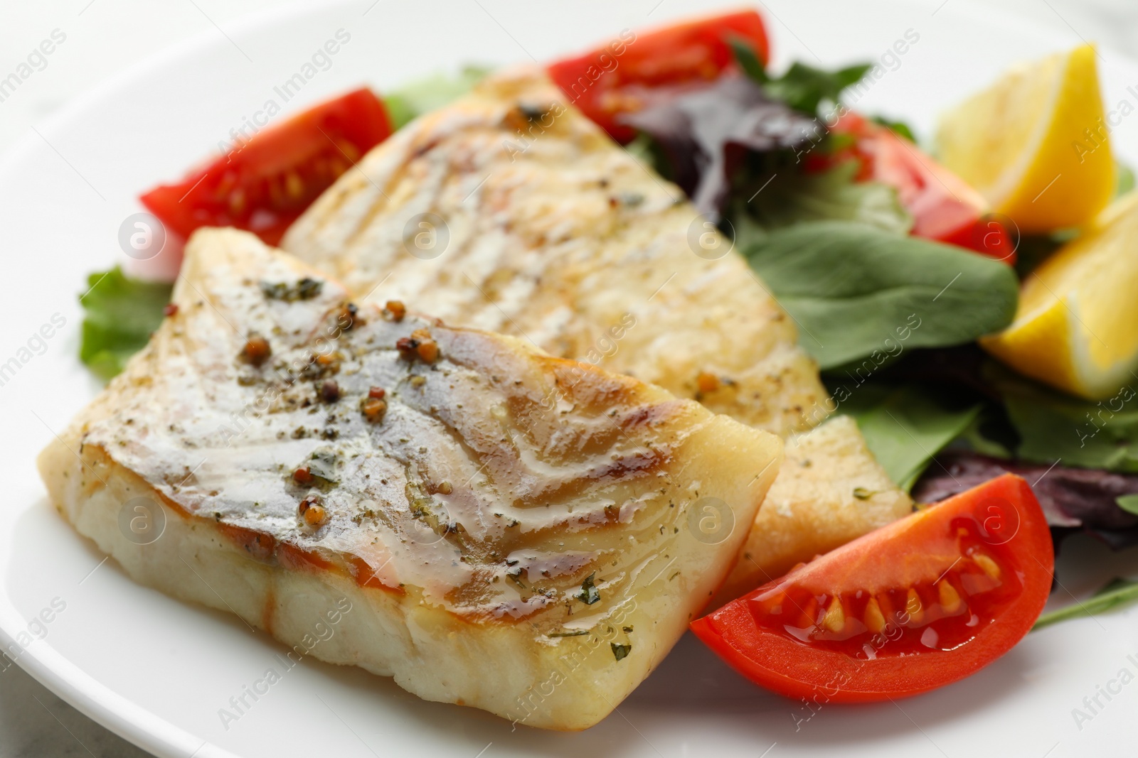 Photo of Tasty cod cooked with salad on table, closeup