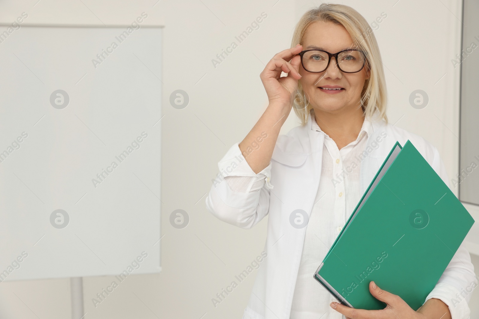 Photo of Professional doctor wearing medical coat near flipchart board in clinic