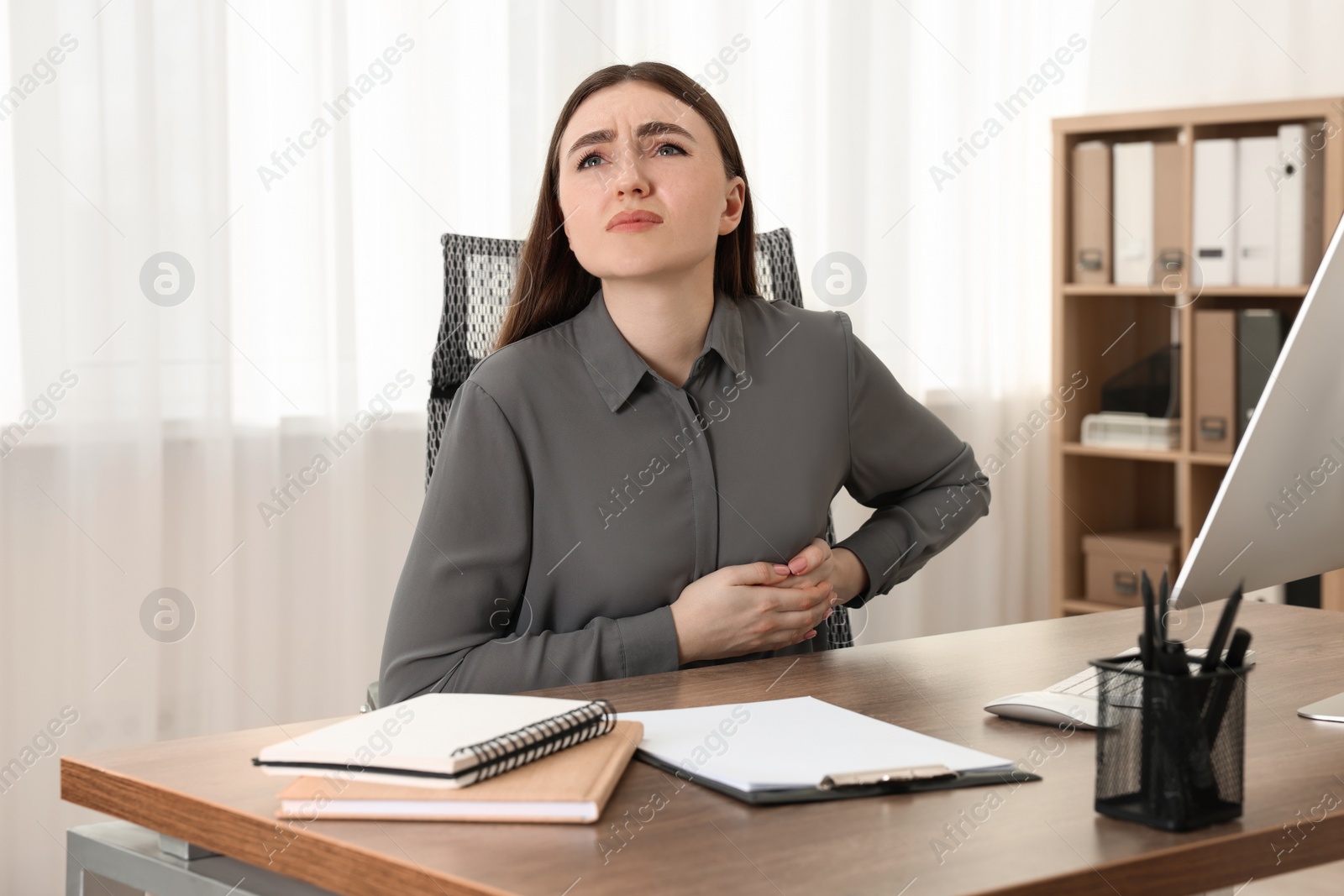 Photo of Woman having heart attack at table in office