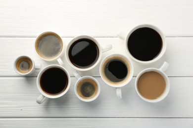 Photo of Different coffee drinks in cups on white wooden table, flat lay