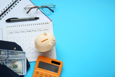 Flat lay composition with piggy bank and calculator on light blue background. Space for text