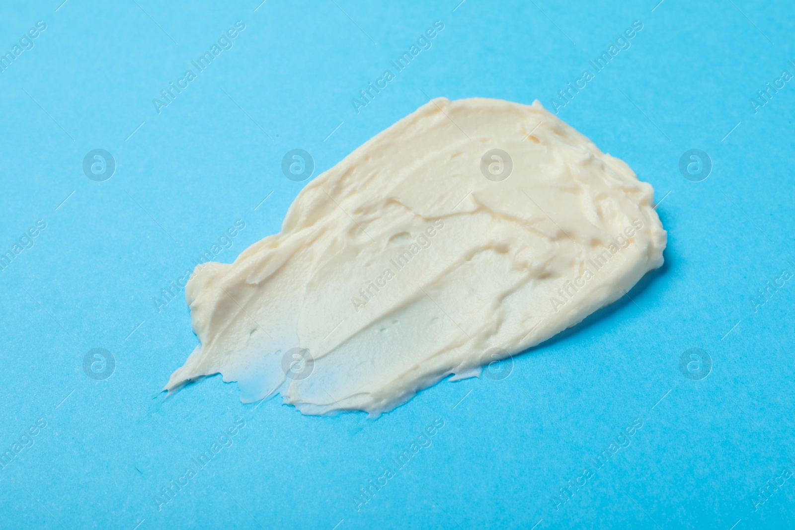 Photo of Smear of delicious cream cheese on light blue background, top view