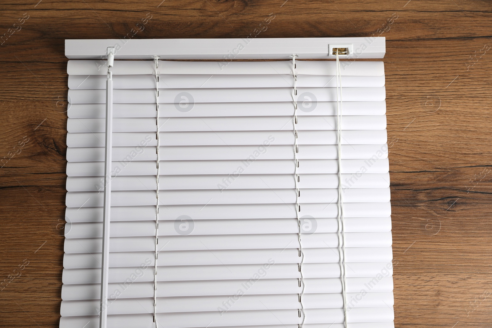 Photo of Stylish horizontal window blinds on wooden table, top view