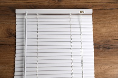 Photo of Stylish horizontal window blinds on wooden table, top view