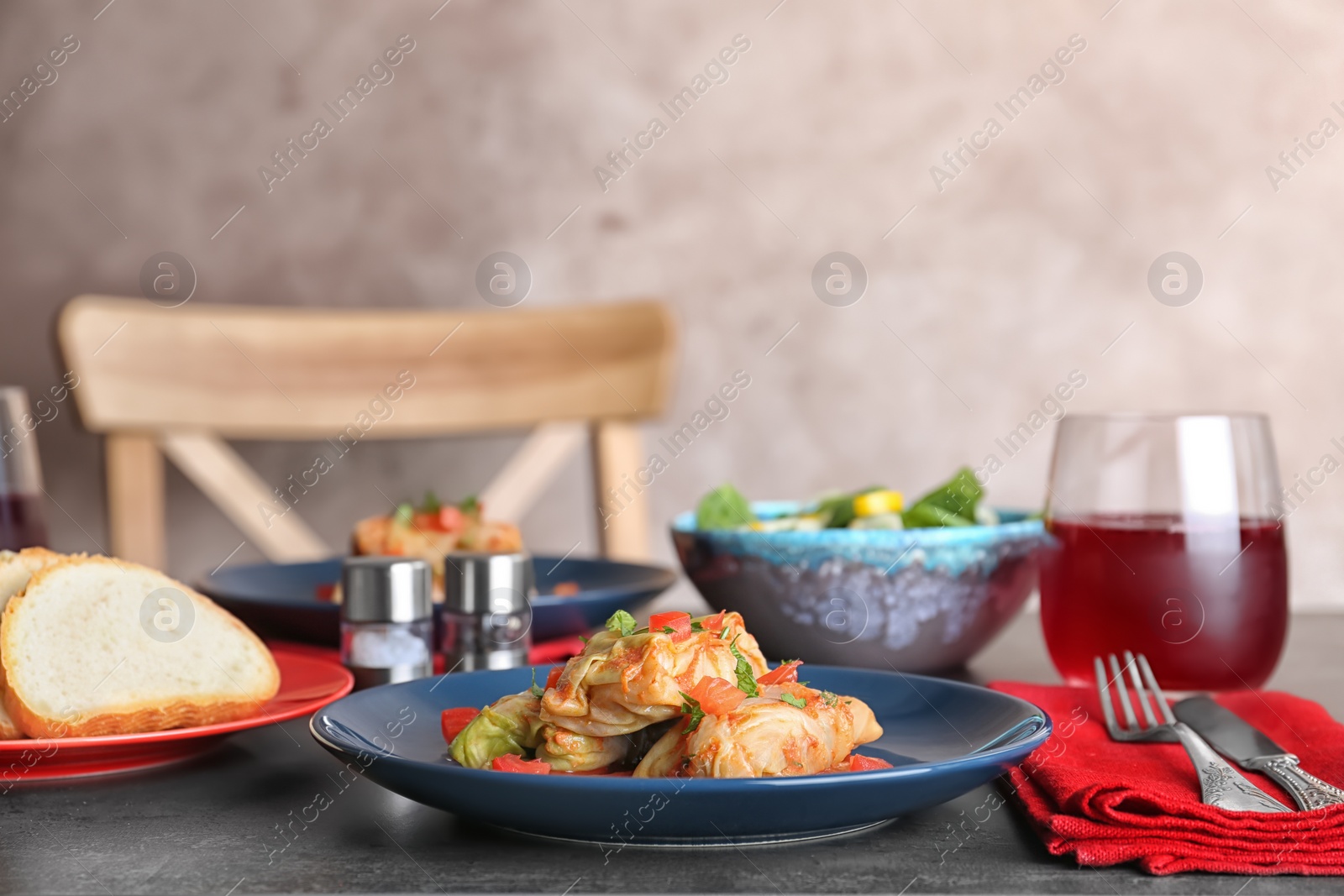 Photo of Plate with stuffed cabbage leaves in tomato sauce on table