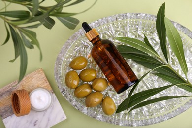 Photo of Cosmetic products, olives and leaves on green background, flat lay