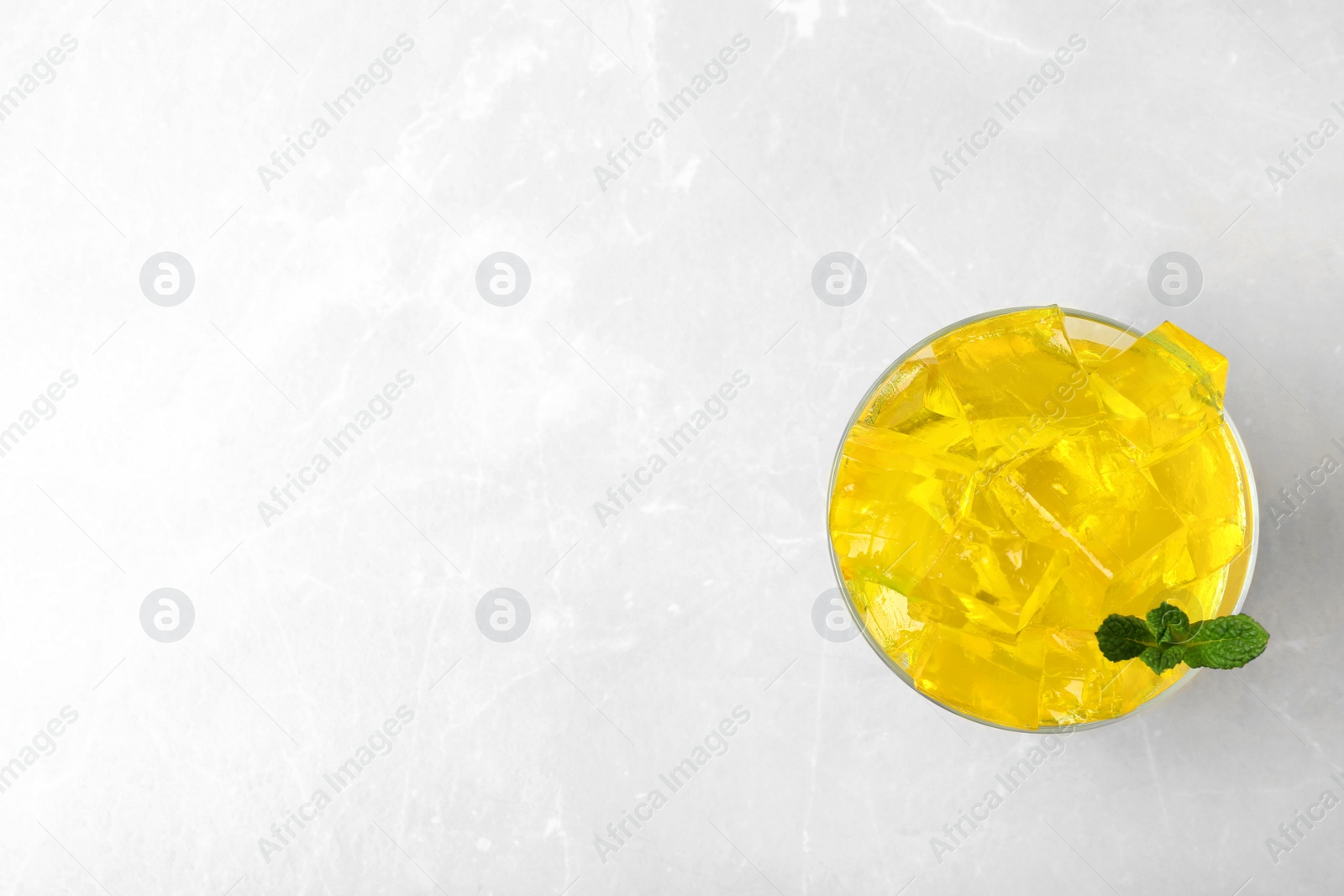 Photo of Glass bowl of tasty jelly cubes on table, top view with space for text