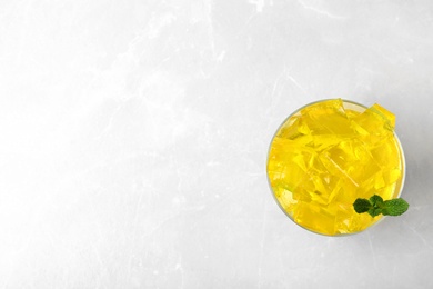 Photo of Glass bowl of tasty jelly cubes on table, top view with space for text