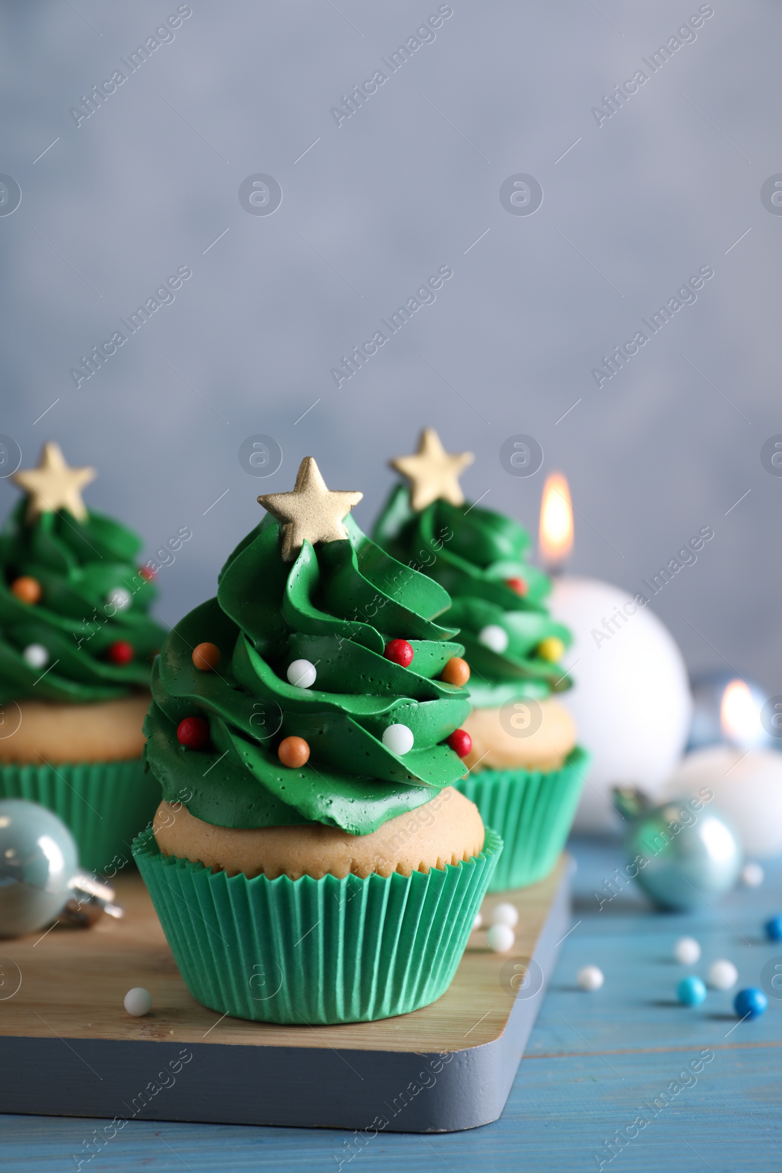 Photo of Christmas tree shaped cupcakes and decor on light blue wooden table