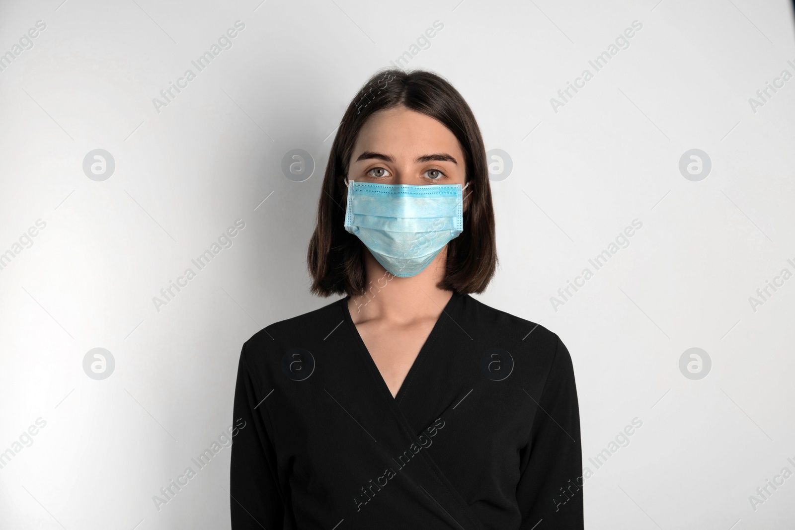 Photo of Woman with disposable mask on face against white background