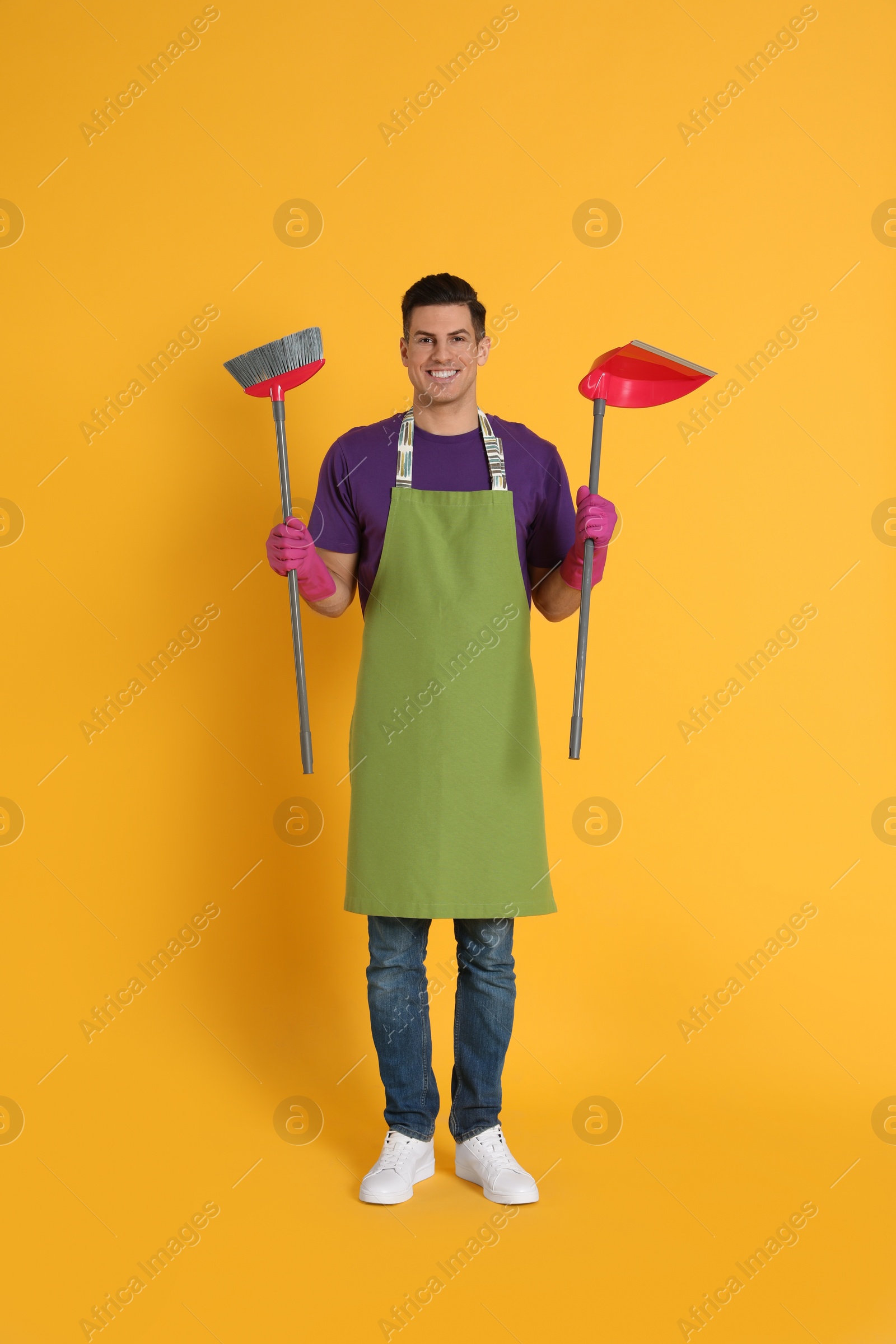 Photo of Man with broom and dustpan on orange background