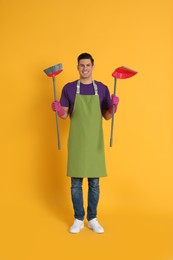 Man with broom and dustpan on orange background