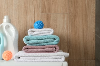 Photo of Dryer balls, stacked clean towels and detergents on washing machine. Space for text