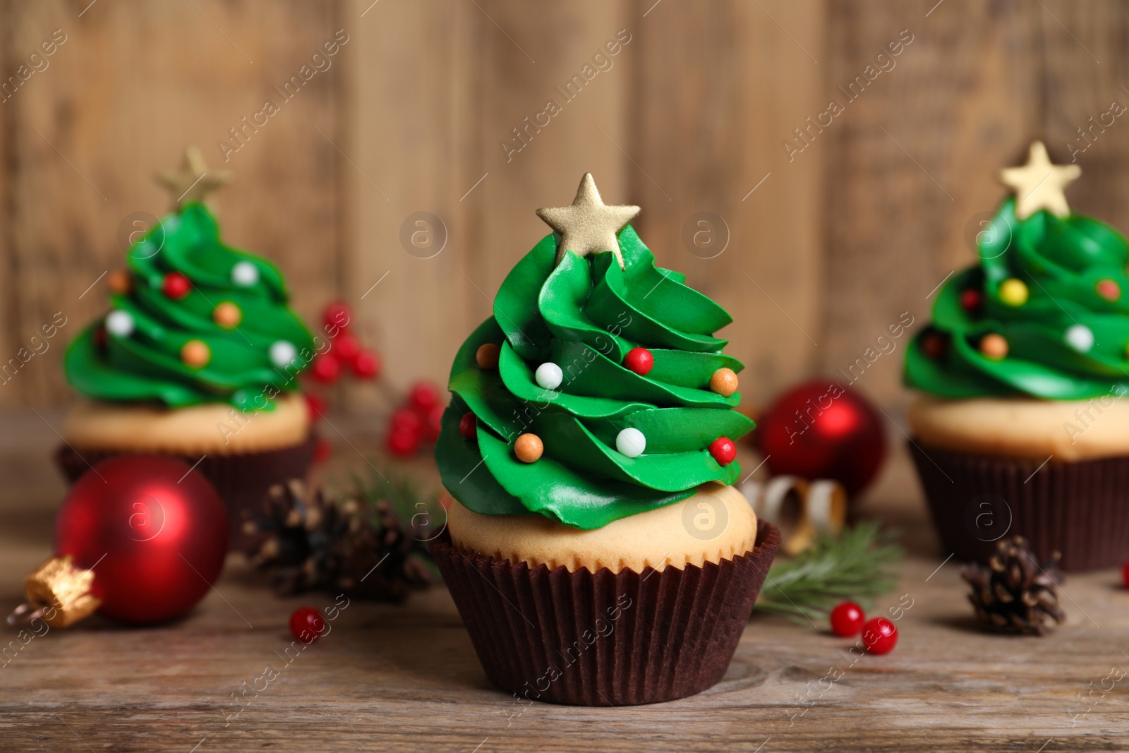 Photo of Christmas tree shaped cupcakes on wooden table