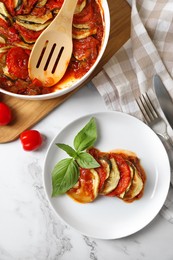 Delicious ratatouille served with basil on white marble table, flat lay