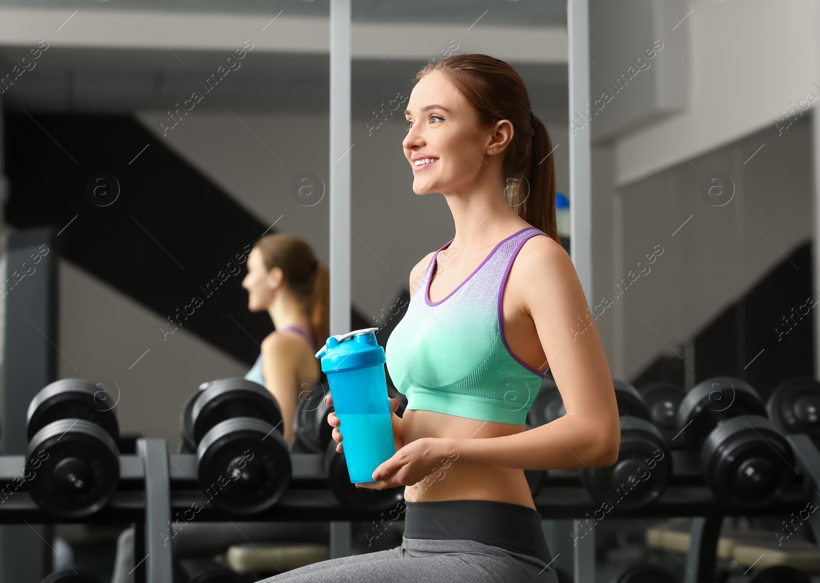 Photo of Athletic young woman with protein shake in gym