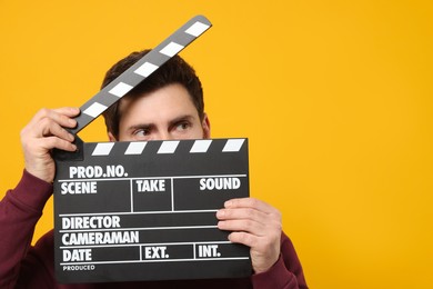 Photo of Actor holding clapperboard on orange background, space for text