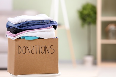 Photo of Donation box with clothes on table indoors