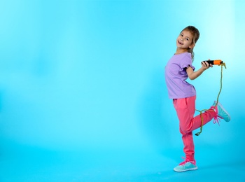 Full length portrait of girl with jump rope on color background, space for text