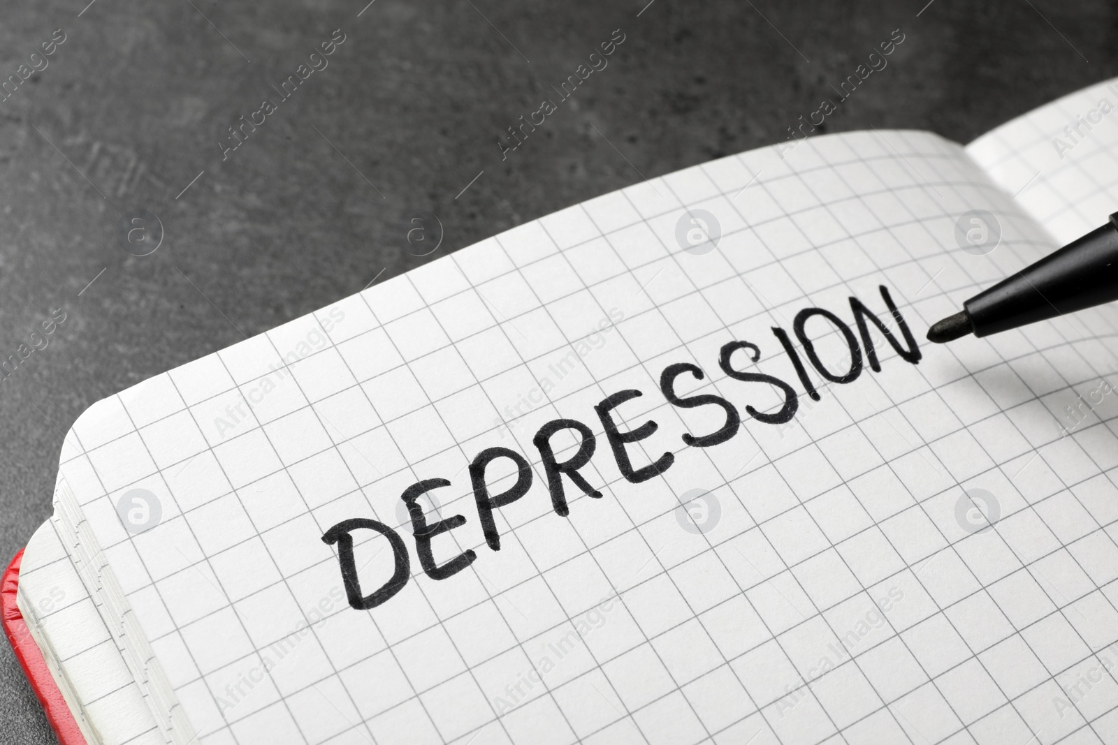 Photo of Writing word Depression in notebook on table, closeup